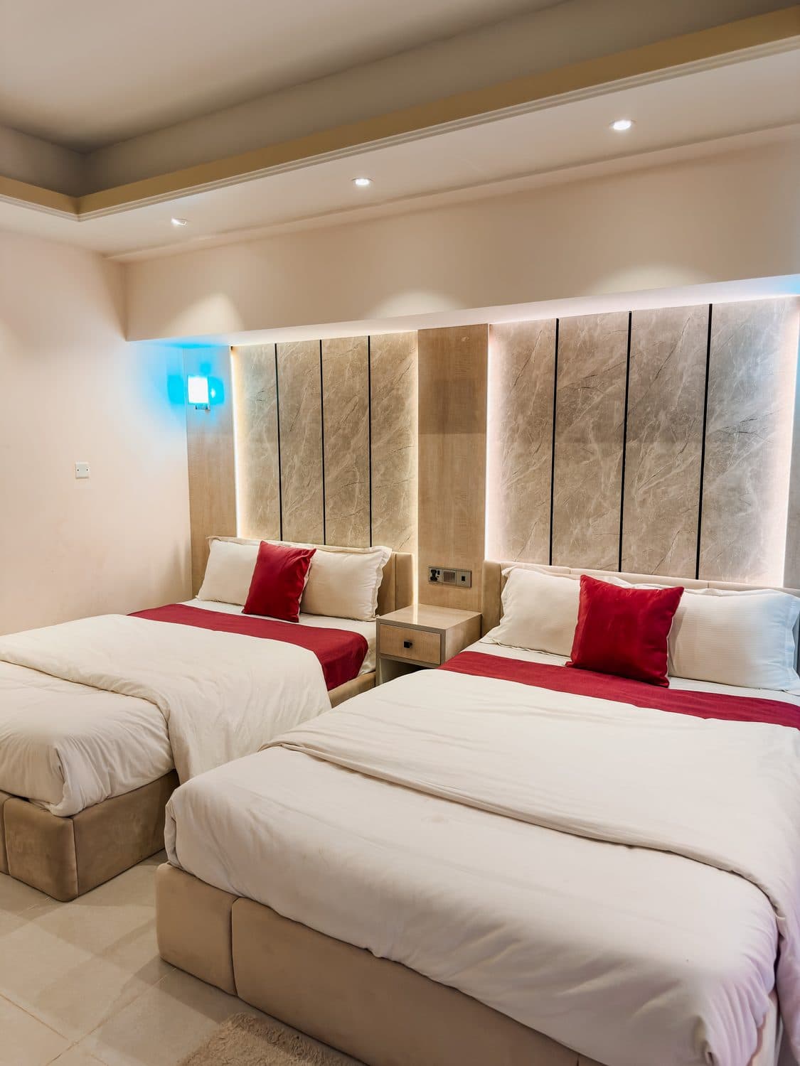 Twin beds dressed with red accent pillows